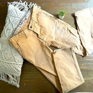 Distressed faded tan yellow slim cut jeans.
